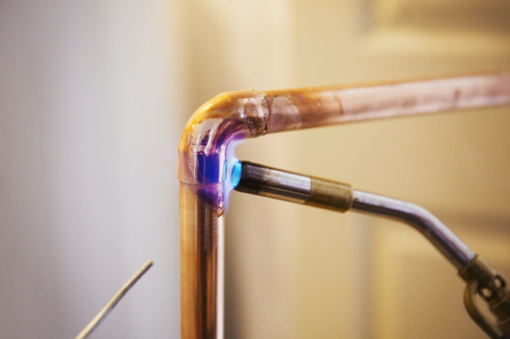 Close up of a copper pipe being welded.